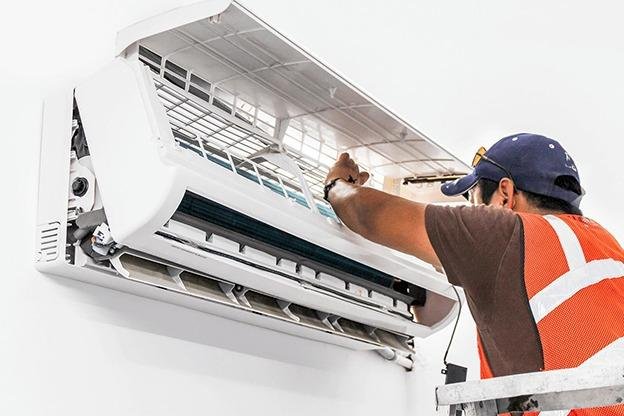Technician repairing and gas-charging an air conditioner